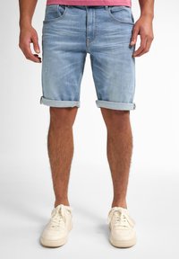 Bermuda in denim azzurro chiaro con risvolti, caratterizzati da una texture leggermente sbiadita e tasche frontali. Abbinati a sneakers bianche con lacci.
