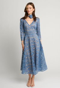 Niebieska koronkowa sukienka z rękawami do trzech czwarte, dekoltem w serek i kwiatowymi wzorami. Rozszerzany krój spódnicy w połączeniu z pasującą koronkową chokerem.