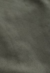 Tissu texturé de couleur vert foncé avec un aspect doux et suédé, présentant une surface uniforme et sans motifs ni accents visibles.