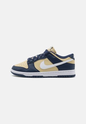 Zapatillas Nike Dunk Low con una combinación de cuero azul marino, amarillo y blanco. Punta perforada, diseño con cordones y suela de goma.