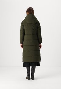 Lange, donkergroene pufferjas met een capuchon, voorzien van horizontale quilted secties, een lange silhouet en drukknoopdetails aan de zoom.