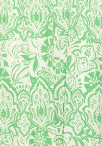 Tissu vert et blanc avec des motifs floraux et paisley complexes créant un design symétrique et répétitif.