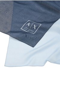 Sciarpa blu e azzurro chiaro con una sottile trama ondulata. Include un'etichetta con logo bianco nell'angolo e tessuto morbido e leggero.
