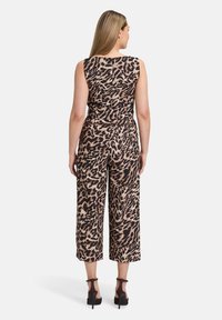 Leopárd mintás kezeslábas, széles lábakkal, ujjatlan kivitelben, sima anyagból készült. Feszes derékkal és hátsó cipzárral rendelkezik.