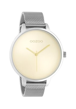 Montre ronde en métal avec un bracelet en maille argentée, cadran doré clair, design minimaliste, aiguille des heures et des minutes dorées. Logo de la marque : OOZOO.