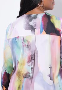 Bunte, mit abstrakten Mustern gestaltete Bluse mit einer glatten, seidigen Textur. Verfügt über einen lockeren Schnitt und einen Rückenfalten für zusätzlichen Komfort.