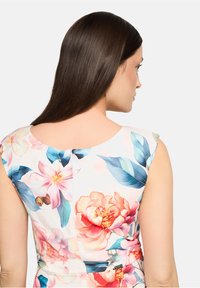 Robe fleurie avec un grand motif floral en rose et bleu, dotée d'un col arrondi et de manches courtes. Tissu lisse avec une sensation de légèreté.