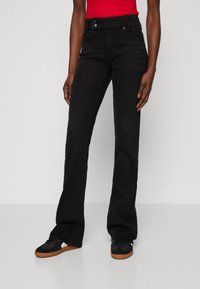Vaqueros acampanados negros de cintura alta, con cierre de botón y cremallera, y bolsillos frontales. Tejido de denim suave y detalles de costura mínimos.
