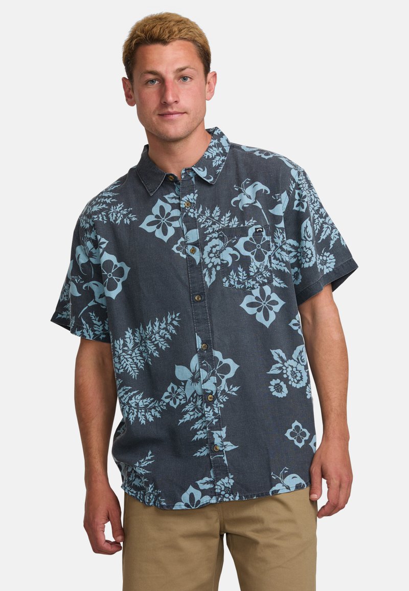 Camisa de manga corta, con botones, en tela oscura con un gran patrón floral en azul claro y sutiles diseños de hojas; presenta un bolsillo en el pecho.