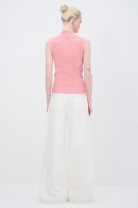 Roze geribbelde mouwloze top met een hoge hals, gecombineerd met crèmekleurige broek met wijde pijpen, voorzien van achterzakken en contrasterende stiksels.