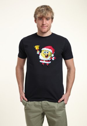 Sort t-shirt med et trykt design af en tegneseriefigur i julemandskostume, med hvid pelskant og en rød hat, der holder en klokke.