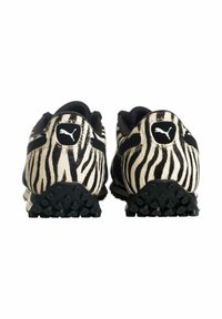 Scarpe sportive a righe bianche e nere con tomaia testurizzata, dotate di un piccolo logo sul tallone e suola in gomma nera con tacchetti.