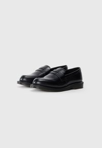 Zwarte leren loafers met een gladde textuur, ronde neus en dubbele riemaccenten. Rubberen zolen bieden grip en duurzaamheid.