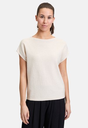 Haut texturé ivoire à manches courtes avec un col rond. Présente une coupe ample et un tissu doux. Porté avec un pantalon décontracté noir.