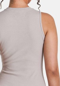 Lichtgrijze tanktop met een geribbelde textuur, met een ronde halslijn en een mouwloos ontwerp, dat de achterkant en schouderpartij van de top laat zien.