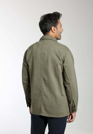 Veste-chemise vert olive avec col, poignets à boutons et une poche arrière unique. Fabriquée en tissu robuste avec une texture lisse.