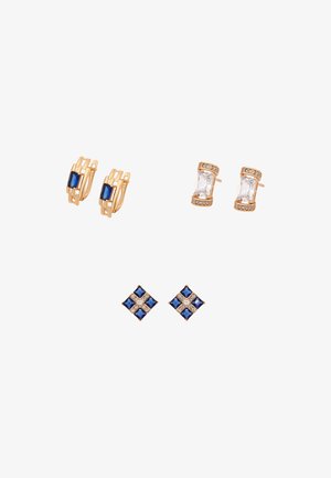 Drie paar gouden oorbellen: creolen met blauwe edelstenen, heldere rechthoekige studs met kleine kristallen, en blauw- en heldere diamantvormige studs.