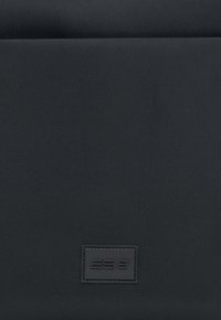 Czarna torba z teksturowanej tkaniny z gładką, prostokątną skórzaną łatą z wytłoczonym logo "ES8". Prosty design z subtelnymi detalami.