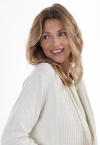 Lys creme cardigan med et struktureret frontpanel og glatte ærmer, der har subtile syninger og en afslappet pasform.