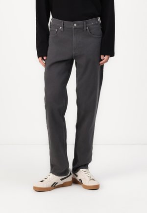 Gray denim pants with a relaxed fit, front pockets, and subtle stitching details, paired with white sneakers featuring black accents.