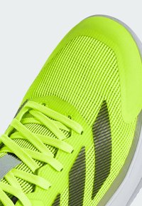 Chaussure de course vert néon vif avec tige en mesh, lacets assortis et motif rayé noir près de la zone des orteils sur semelle blanche.