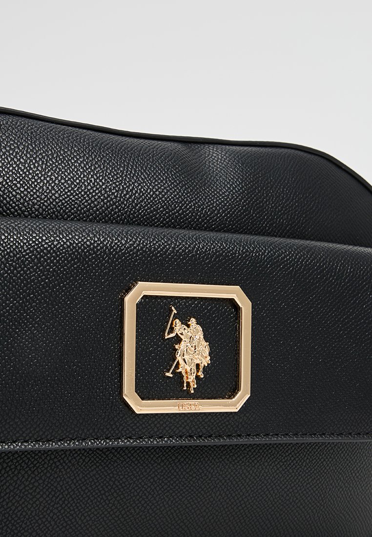 Sac en cuir noir texturé avec une plaque logo rectangulaire en ton or présentant un design équestre à l'avant. Bords lisses et forme structurée.