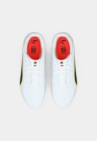 White athletic shoes with a smooth texture, featuring black and yellow accents along the sides and bright red insoles with QR codes.