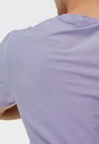 T-shirt de sport violet à évacuation de l'humidité, en tissu texturé et à manches courtes, avec un col rond et une coupe décontractée.