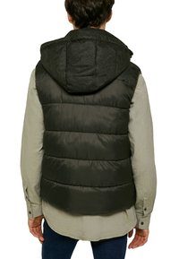 Vadderad svart väst med en texturerad huva, med en strukturerad design och horisontellt quiltade sektioner, som bärs över en ljusgrå skjorta.