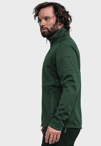 Green fleece jacket with a high collar, side zip pocket, and long sleeves. Features smooth texture and subtle brand logo on the shoulder.