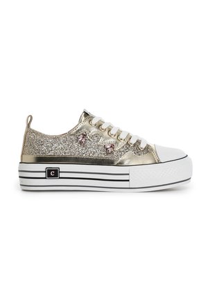 Zapatillas brillantes doradas con puntera de goma blanca y suela de plataforma. Presentan acentos de flores rosas y una base a rayas en blanco y negro.