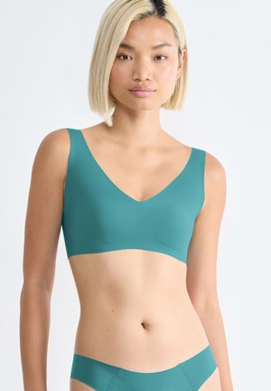 Soutien-gorge teal avec un décolleté en V et de larges bretelles, fabriqué en matériau lisse. La ceinture assortie complète l'ensemble.