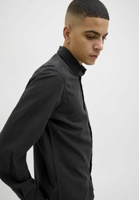 Cămașă neagră cu nasturi, realizată dintr-un material texturat, având o guler și manșete lungi, cu o croială elegantă și închidere frontală cu nasturi.