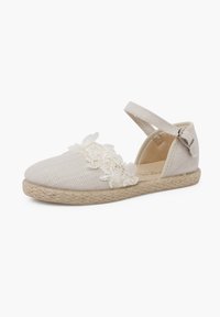 Chaussure de style espadrille en tissu texturé beige, avec des accents en dentelle florale et une semelle en jute tissée. Bride de cheville ajustable.