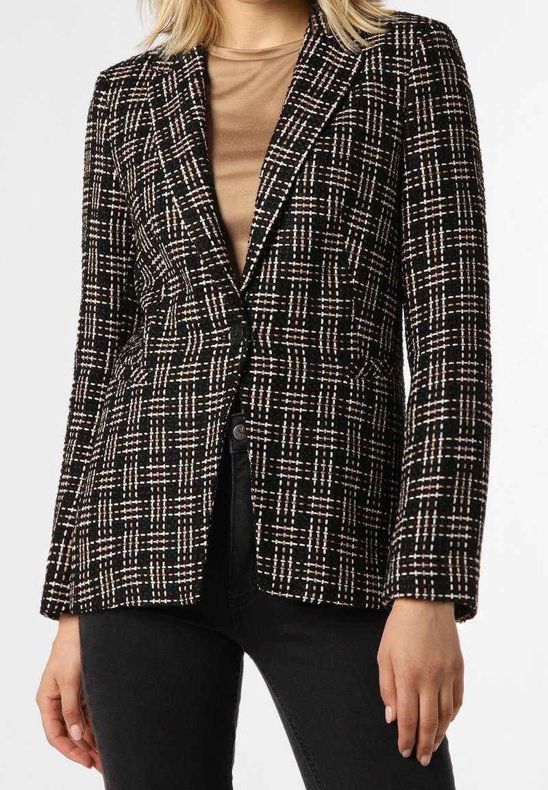 Blazer à carreaux noir et blanc avec une finition texturée, doté d'une fermeture à un bouton et de revers crantés, associé à un haut beige.
