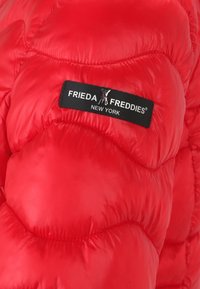 Rød pufferjakke med quiltet design, skinnende materiale og et sort mærke med teksten "FRIEDA FREDDIES NEW YORK".
