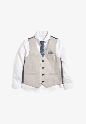 Hvid langærmet skjorte med beige vest med knapper, marineblåt slips med fuglemønster og mønstret lommetørklæde mod hvid baggrund.