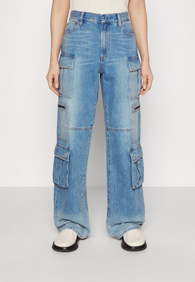 Vaaleansiniset cargo-farkut löysällä istuvuudella, useilla taskuilla ja näkyvillä ompeluyksityiskohdilla. Valmistettu farkkukankaasta, jossa on haalistunut pesupinta.