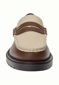 Mocasini din piele maro cu un superior din piele bej, având un design decorativ cu decupaje și o cusătură contrastantă pe o talpă flexibilă de culoare neagră.