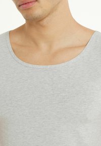 Jasnoszary top na ramiączkach z szerokim, okrągłym dekoltem, miękką teksturą i minimalistycznym designem, odpowiedni na codzienne noszenie.