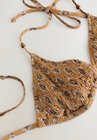 Brunt mönstrad bikinöverdel med smockad textur och justerbara band. Har blommiga detaljer i mörkröd och vit genom hela designen.