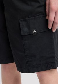 Mustat cargo-shortsit, joissa on sivutasku, säädettävä vyötärö ja pieni logo-tunnus taskun ylle. Valmistettu kestävästä kankaasta, jolla on sileä pinta.