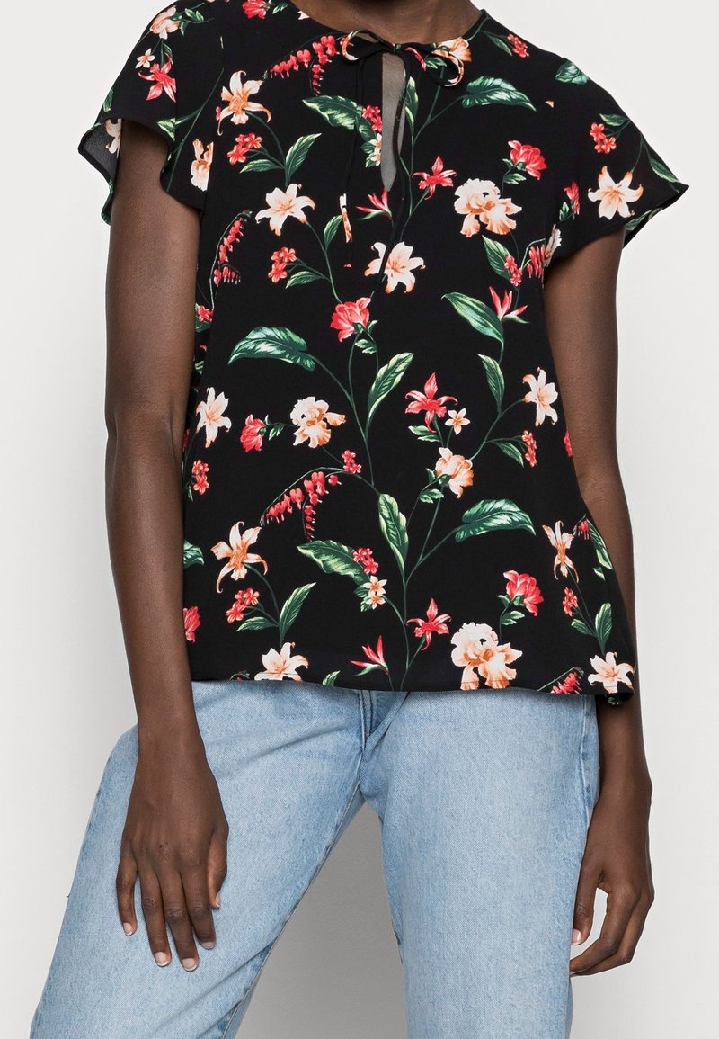 Černá květinová blůza s krátkými rukávy, s vázáním u krku a živým vzorem oranžových a růžových květin s zelenými listy.