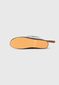 Chaussures à semelle en caoutchouc avec une semelle extérieure orange texturée, dotées d'un dessus bleu marine foncé et d'un accent en cuir au niveau du talon.