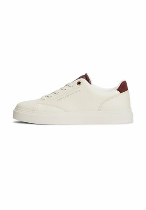Zapatilla deportiva crema de corte bajo con cordones blancos, lengüeta trasera marrón y logo de Tommy Hilfiger en el lateral.