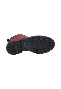 Botte en cuir rouge avec une semelle extérieure en caoutchouc noir, dotée de profondeurs et de grips, conçue pour la stabilité et la traction.