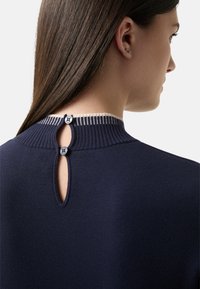 Marineblauer Pullover mit geripptem Kragen und einem Schlitz-Rücken, ausgestattet mit zwei dekorativen Knöpfen. Weiche Textur und minimalistische Designdetails.