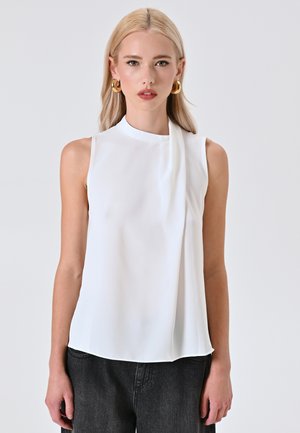 Blouse sans manches blanche avec un col haut et un accent drapé. Fabriquée dans un tissu lisse et léger, elle offre une coupe décontractée.