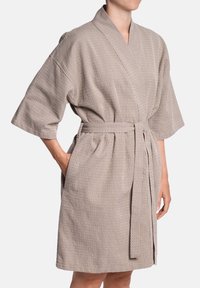 Kimono stila halāts taupe krāsā ar faktūru, ribotu rakstu, platām piedurknēm, jostu viduklī un sānu kabatām. Īsā garumā.