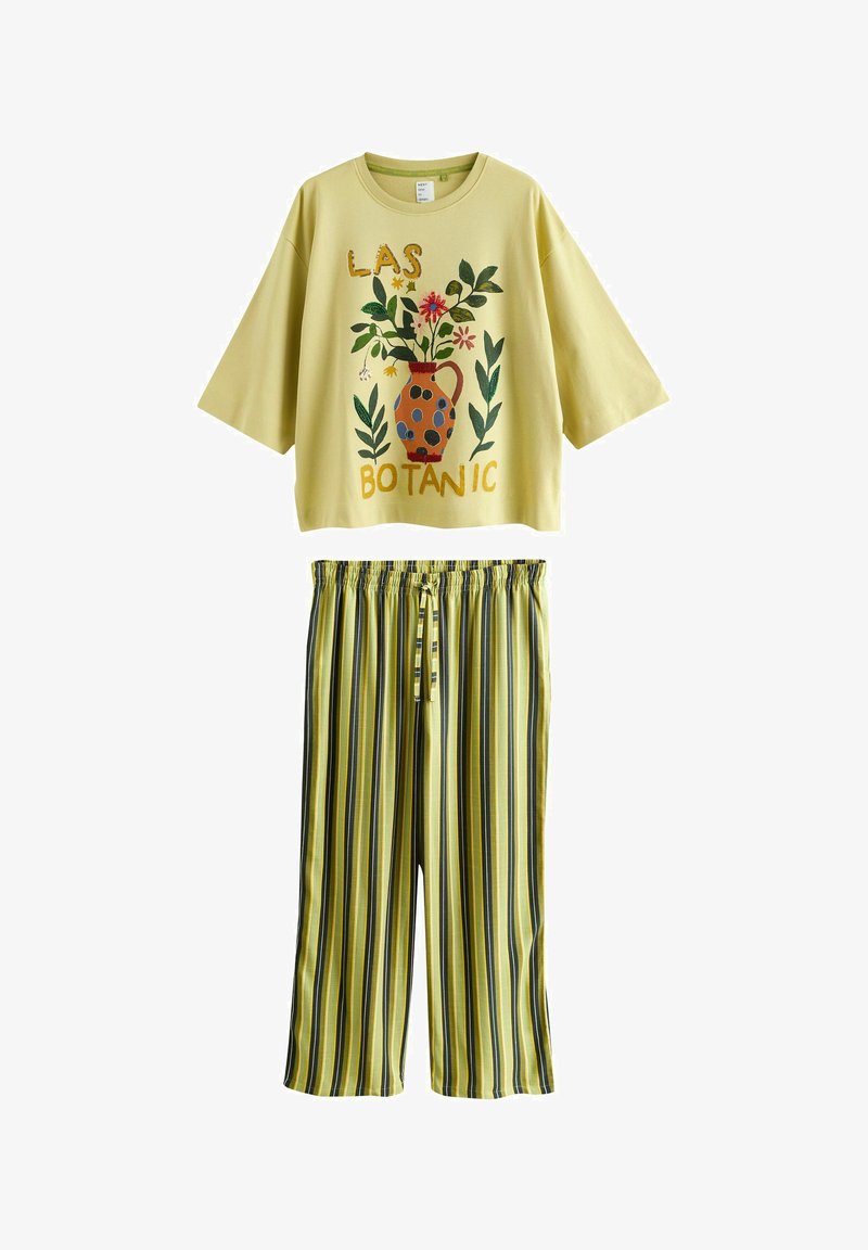 Haut jaune à manches trois-quarts avec imprimé de vase floral et texte "LAS BOTANIC", assorti à un pantalon à rayures verticales jaune, noir et vert.